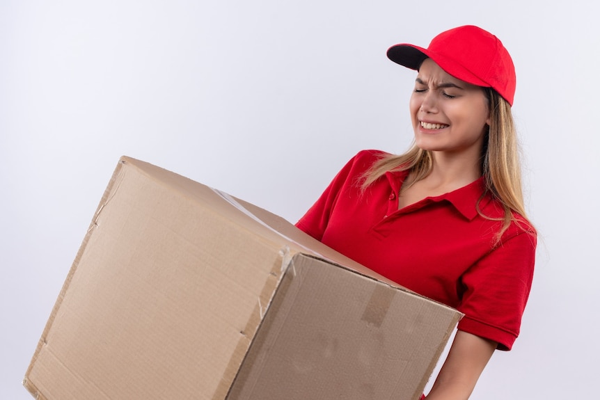 A man in a red uniform lifting a heavy box