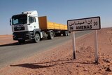 A truck passes by a road sign indicating In Amenas, about 100 km from the Algerian and Libyan border.