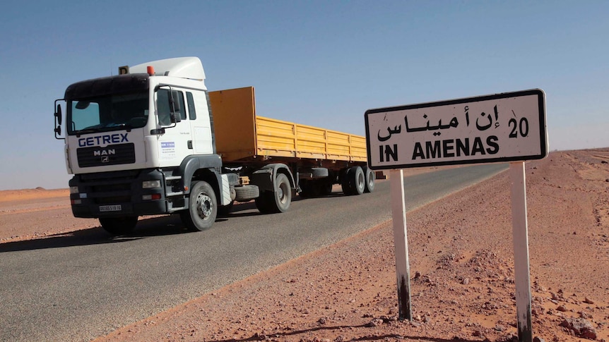 A truck passes by a road sign indicating In Amenas, about 100 km from the Algerian and Libyan border.