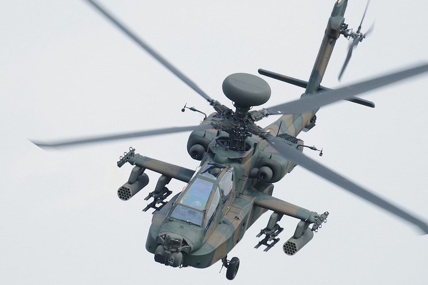 A close-up of a AH-64D military helicopter in the air.