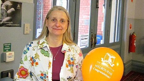 Kerstin Knight smiling in a university building, with a balloon that says 'Congratulations'.