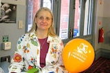 Kerstin Knight smiling in a university building, with a balloon that says 'Congratulations'.