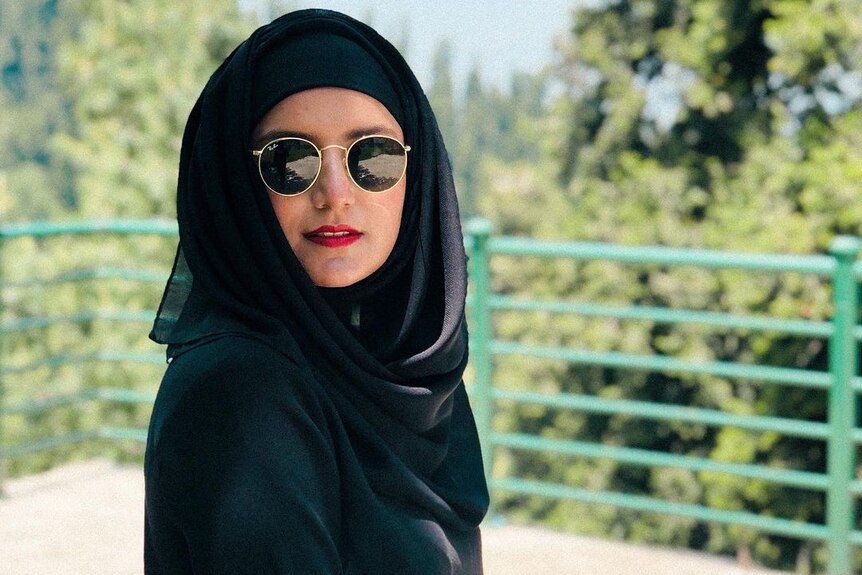 A woman in red lipstick, sunglasses and a hijab