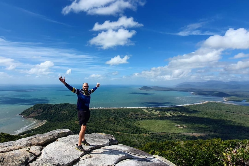 Man standing on mountain with arms out