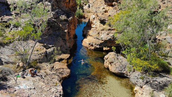 a woman swimming in freshwater among rocks and trees