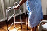 A generic image of an elderly person using a walker in hospital.
