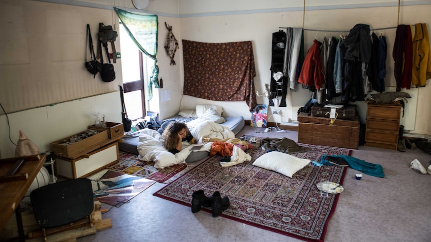 a student lies on a mattress in a share house