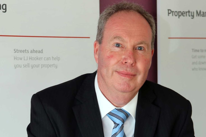 Paul Baird-Murray holds a pen while sitting at his desk.