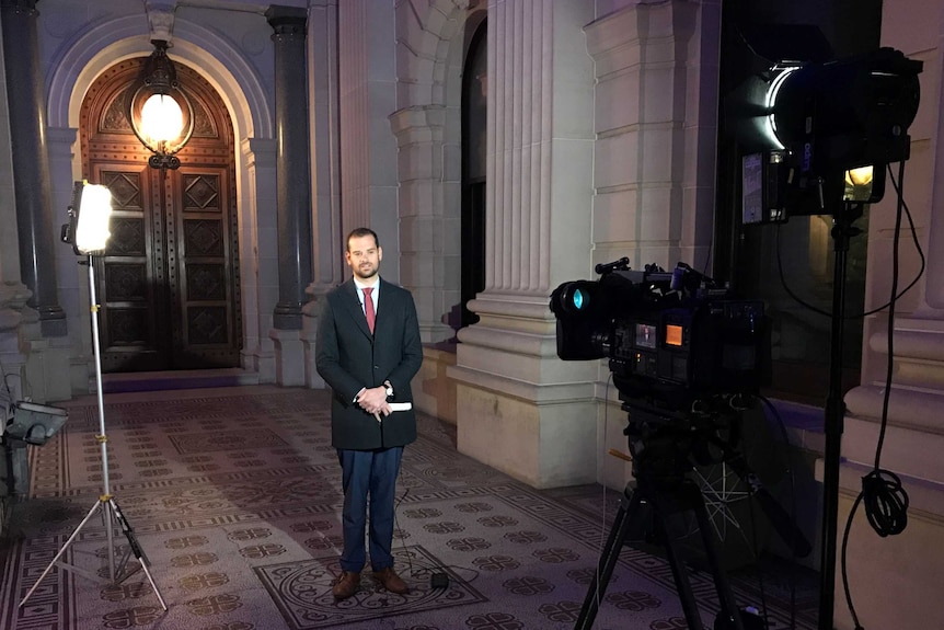 Willingham standing in front of camera and lights at Parliament House in Victoria.
