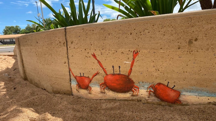 Three small red crabs, in closeup, on the playground edging