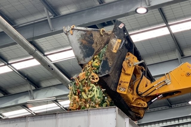 Food scraps including melon rinds and pineapple tops are dumped into the mouth of the waste to energy plant.