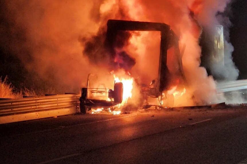A truck on fire on a highway.