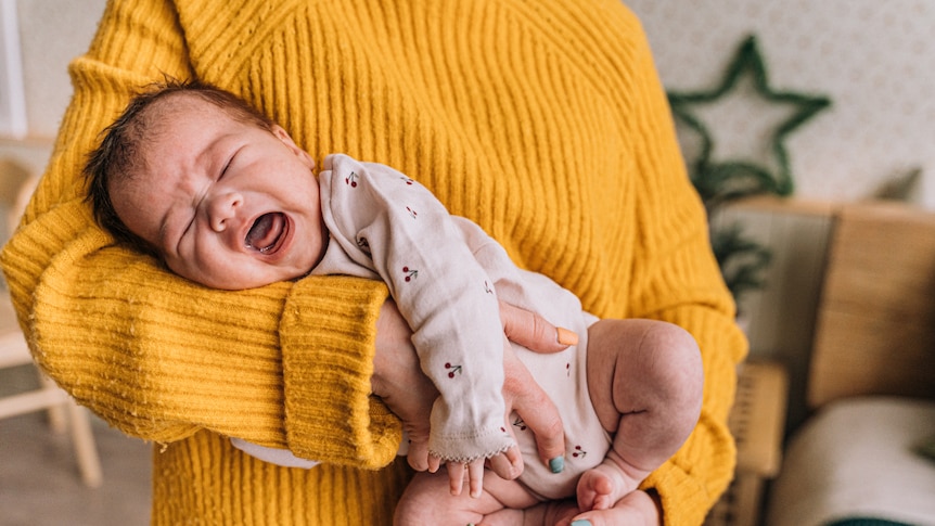 Crying baby in arms of mother.