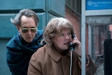Colour still of Richard E. Grant and Melissa McCarthy taking a call at a phonebooth in 2018 film Can You Ever Forgive Me?