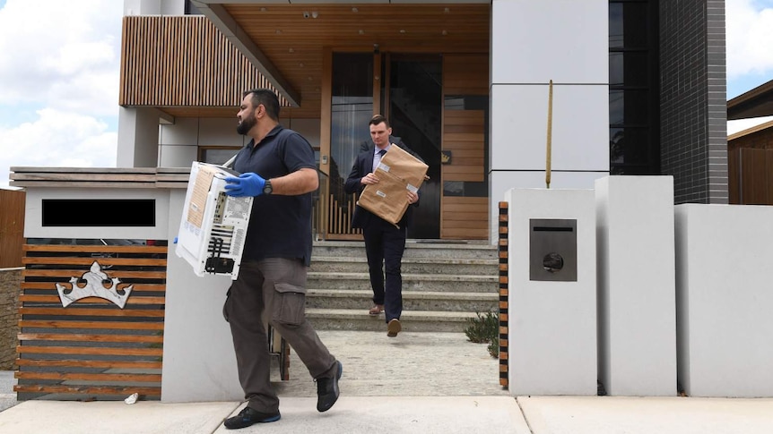 Men carry boxes out of a house.