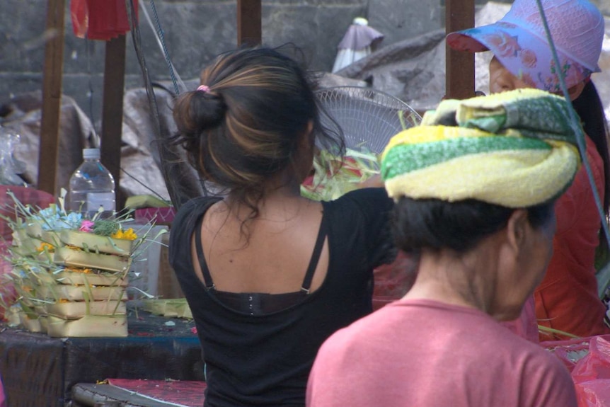 A young girl at a food market, seen from the back.