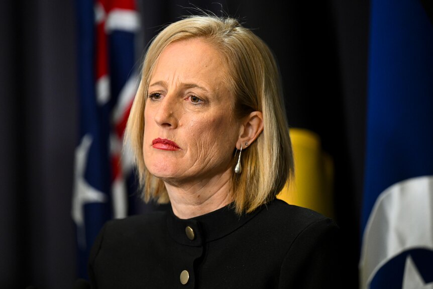 Finance Minister Katy Gallagher, with a serious expression on her face, listens to a question during a press conference.