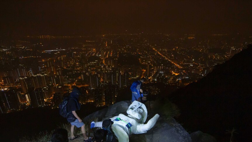 Protestes lay a white statue on a rock atop the peak, looking out over the glittery skyline