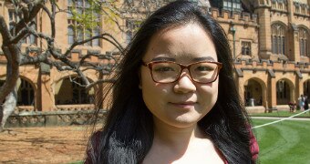 Xi Chen wears tortoise shell framed glasses and stands in the forecourt of UTS.