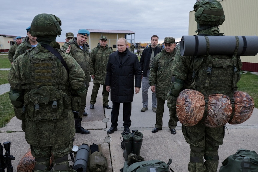Russian President Vladimir Putin listens to members of his military.