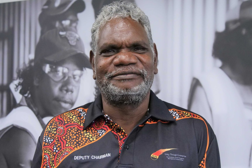 A man stands in front of the camera and smiles.