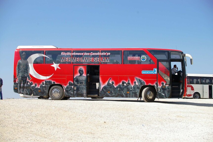 A red tour bus with Turkish writing and images on its sides