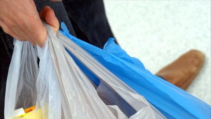 A shopper holds several plastic shopping bags