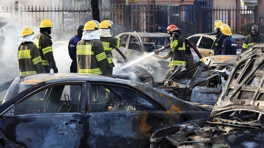 Firefighters douse cars after a deadly bomb blast in Nigeria's capital Abuja