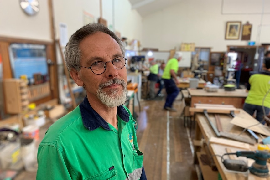 A balding man with glasses inside a workshop