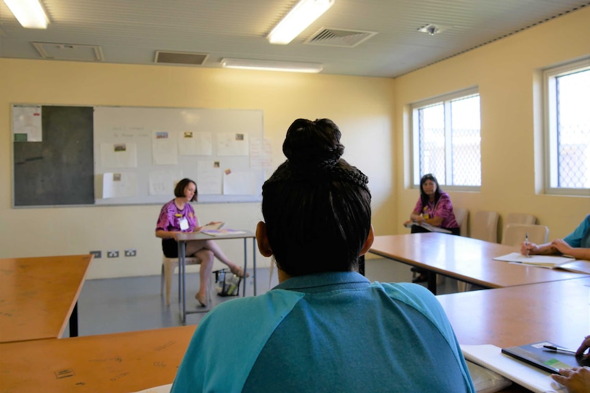 Back of women's head as she sits behind a desk and looks at the facilitators