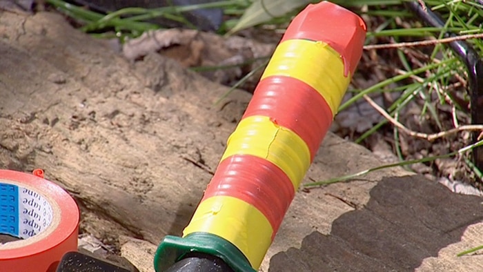 Orange and yellow tape wrapped around the handle of a gardening hand tool