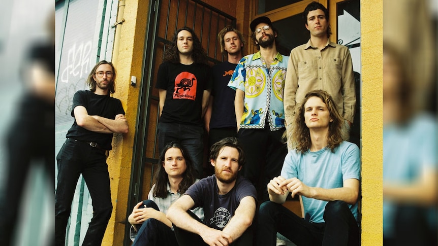 A 2017 press shot of King Gizzard and the Lizard Wizard with Mild High Club's Alex Brittin on the steps of Flightless Records HQ