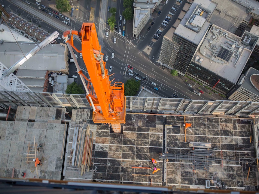 An aerial photo of workers in high-vis clothes on top of a half-built apartment block.