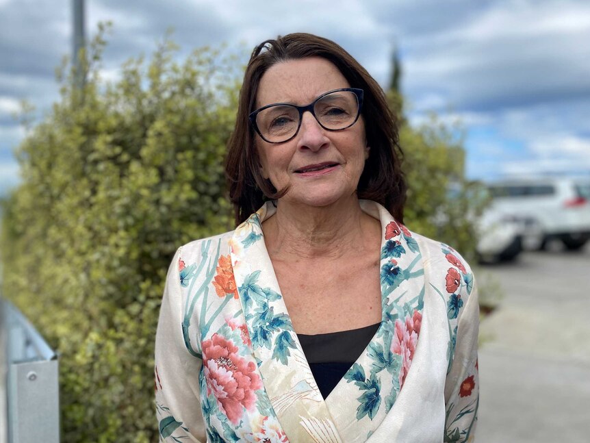 A woman in glasses standing near a tree