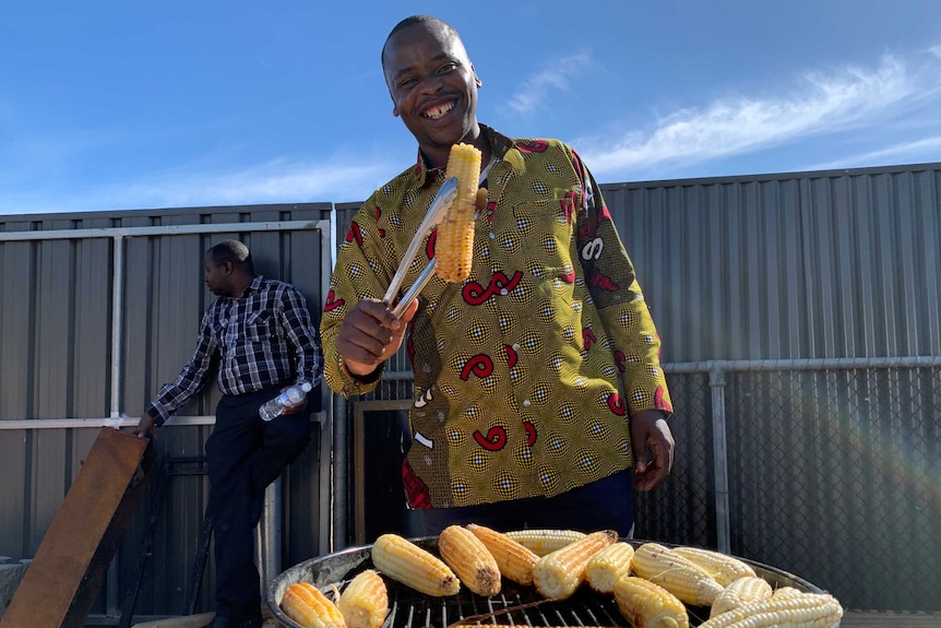 Asheri Bukuru holding freshly-picked maize with silver tongs