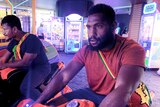 Two men play in a game arcade.