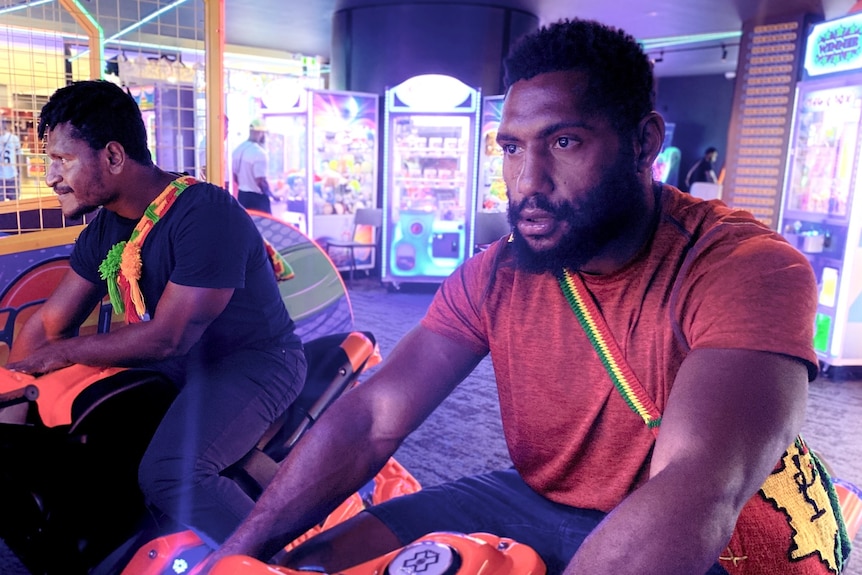 Two men play in a game arcade.