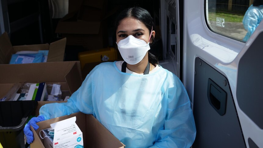 A woman wearing personal protective equipment including a mask.