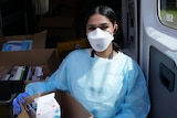 A woman wearing personal protective equipment including a mask.