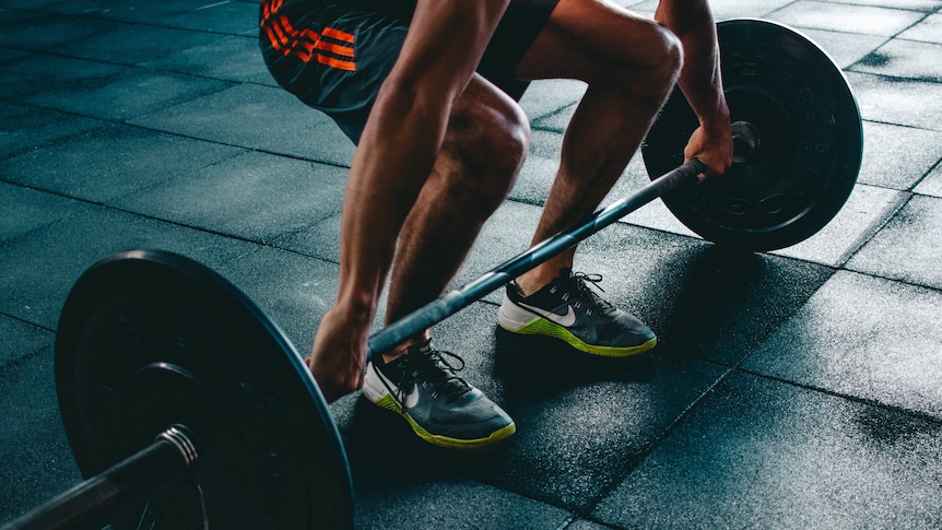 A man holding a barbell, preparing to do a deadlift.