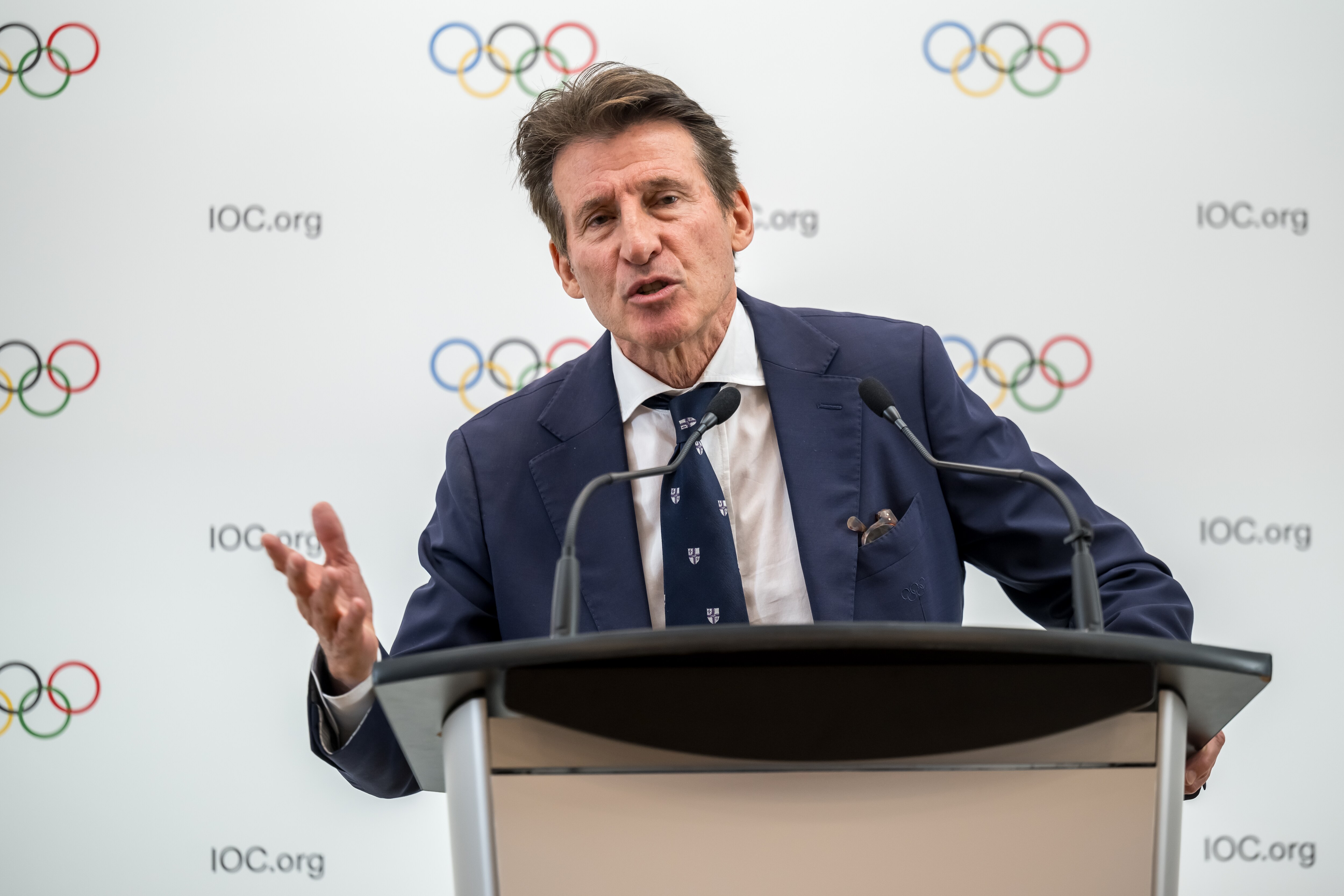 Sebastian Coe speaks at a lecturn and points with his right hand
