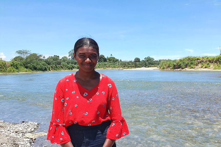 A teenage girl stands on the shoreline of a beach in Solomon Islands.