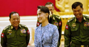 Aung San Suu Kyi smiles with army members.