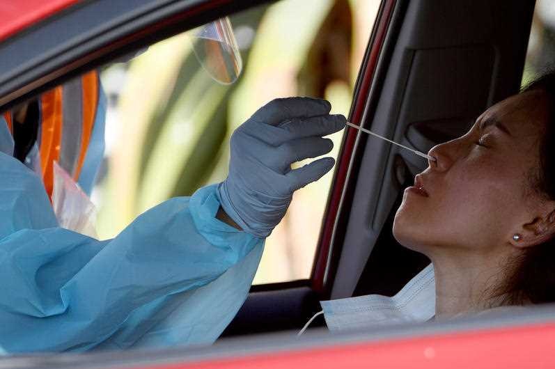 A woman in a car getting a covid swab up her nose.