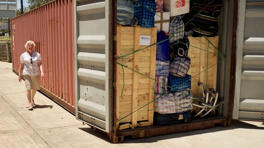 A woman walking near a full shipping container