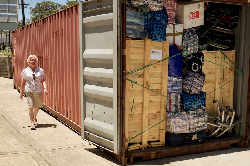 A woman walking near a full shipping container