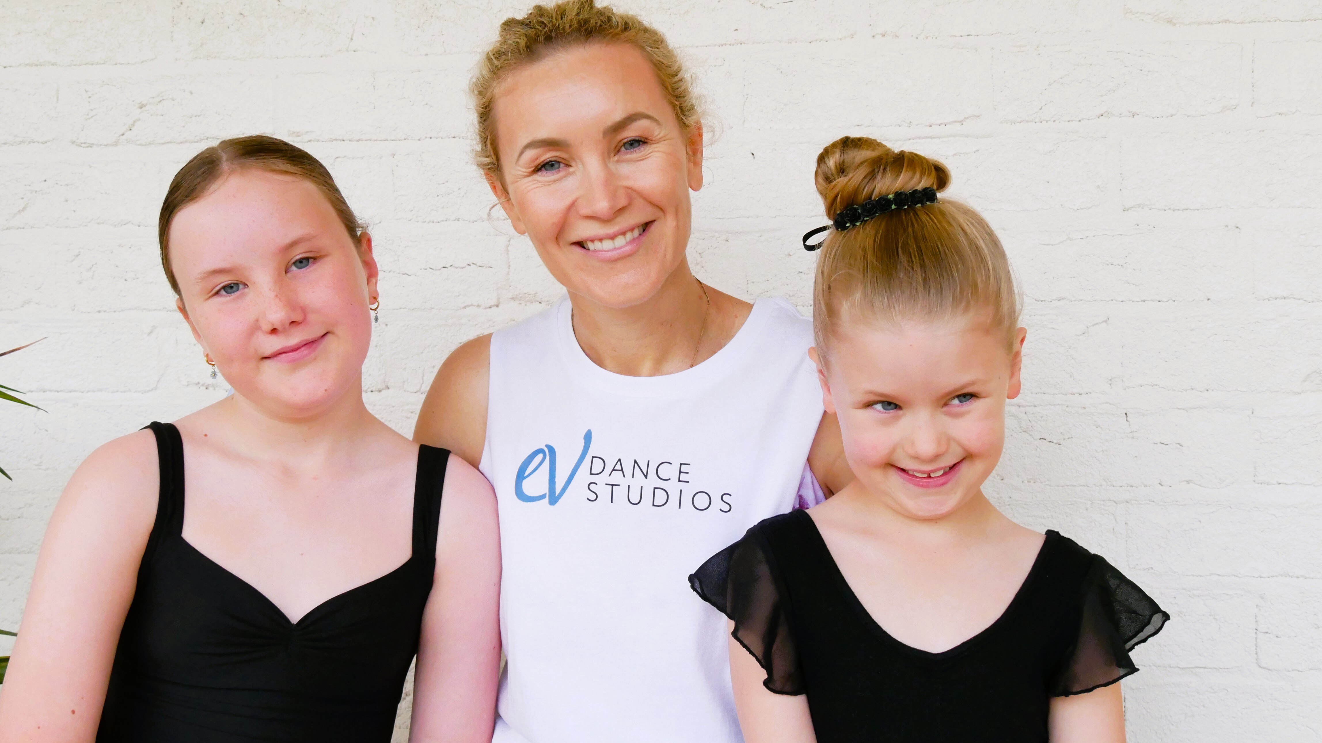 Denise with her daughter's sitting either side of her smiling. 