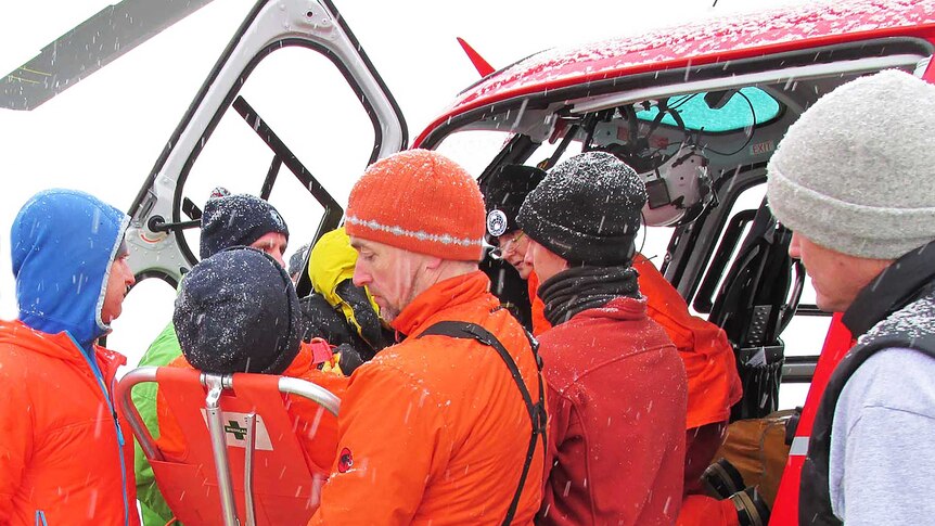 Australian Antarctic Division staff help load an ill expeditioner into a helicopter in Antarctica.