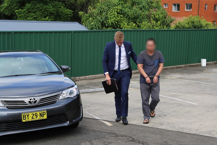 A 56-year-old man is lead away by a detective in a car park after being arrested in Cherrybrook.