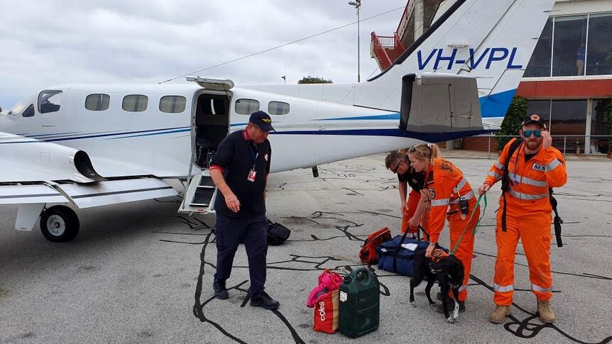 Search volunteers and a dog prepare to board a small plane.